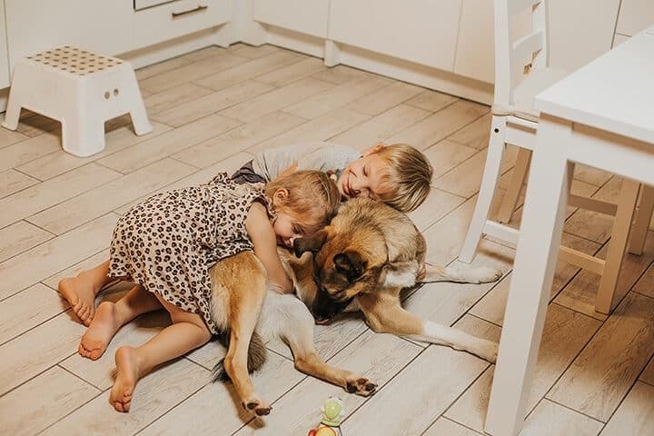 Kids laying on dog on floor